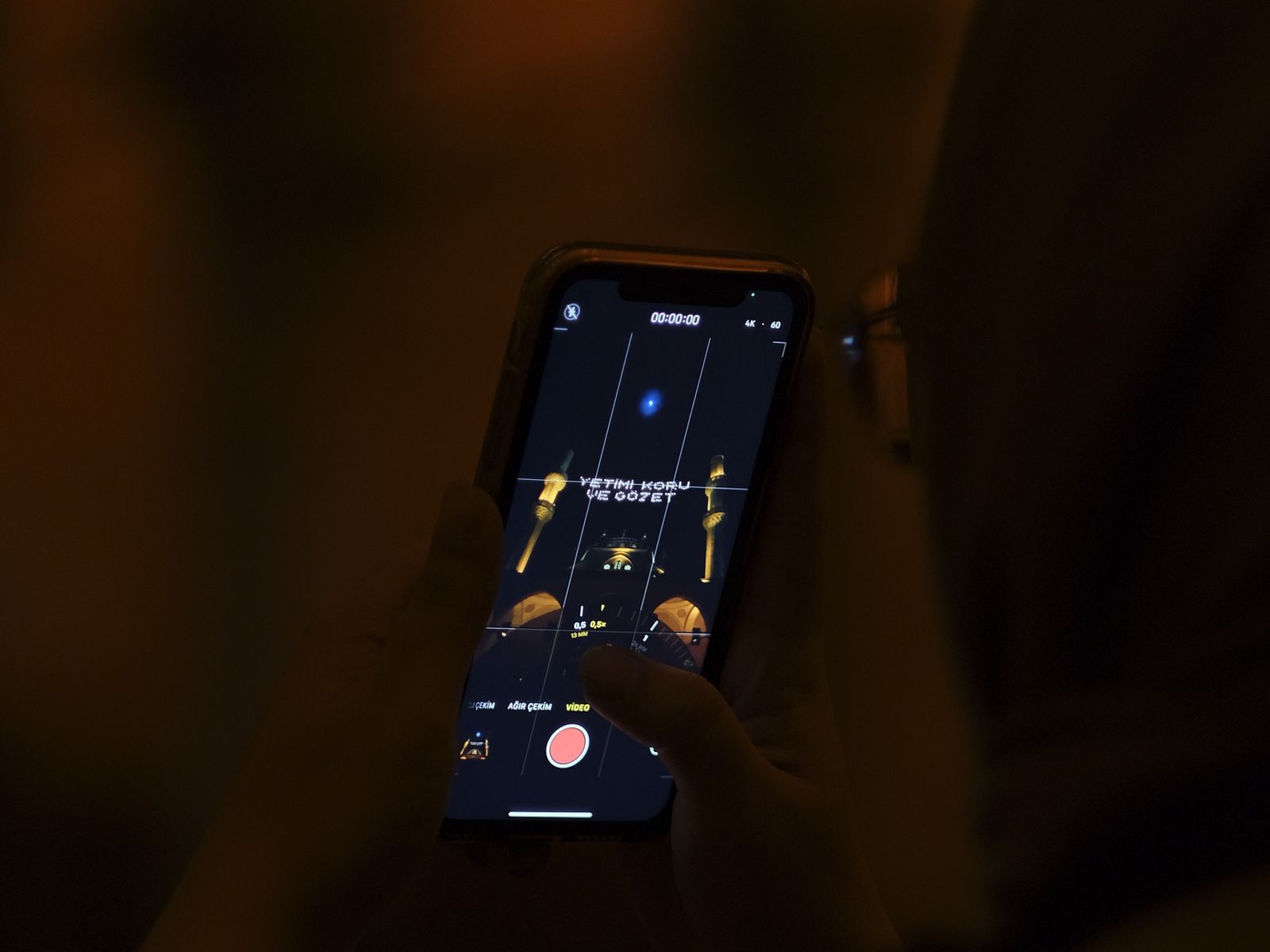 A person filming vertical video on a phone in low light, the mobile-first format Reels post-view ads depend on.